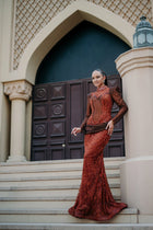Sihëna Carnelian Sarabande — rust high-neck long-sleeve mermaid gown with beaded sheer sleeves and a beaded lace skirt.