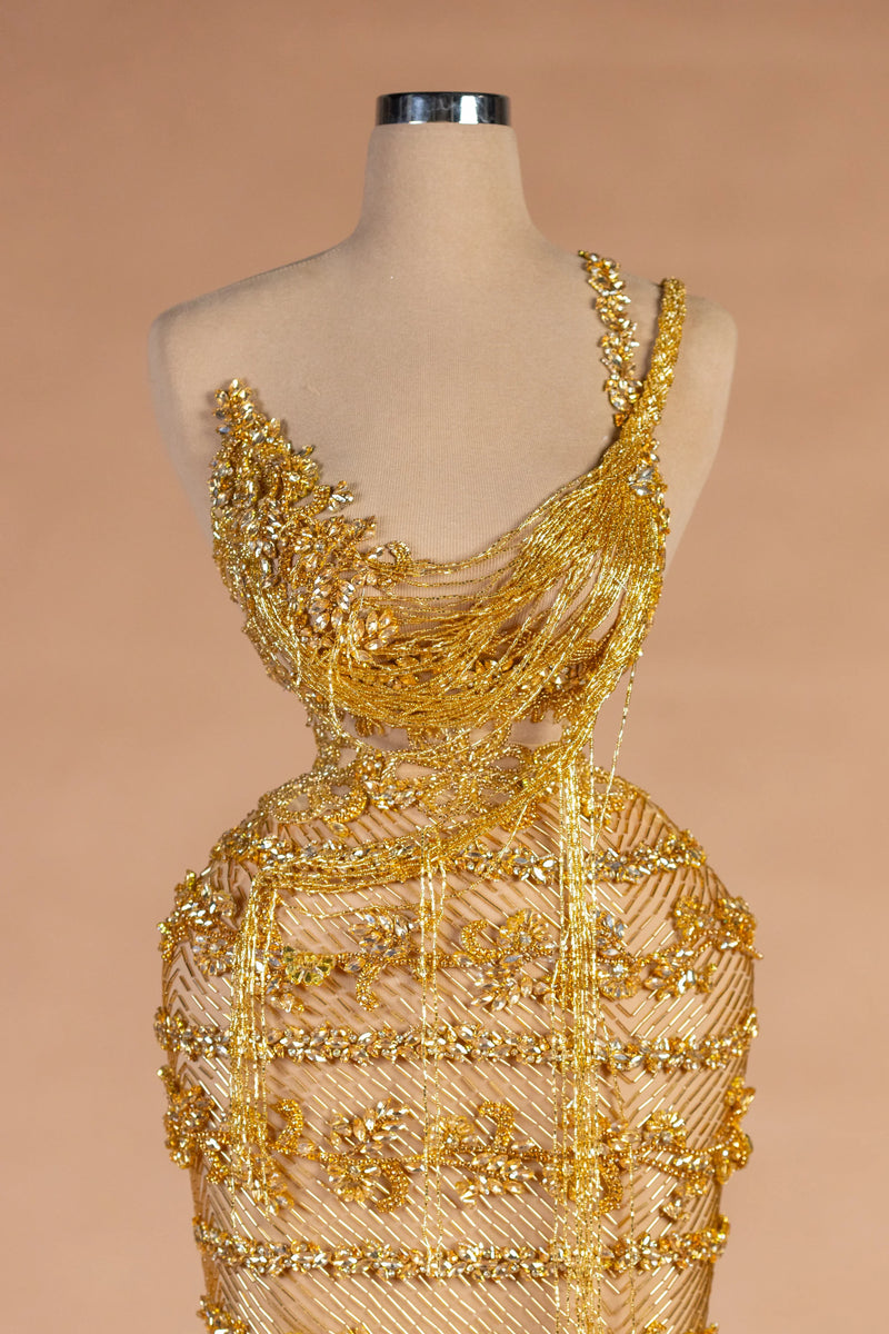 Sihëna حِلْيَةُ التِّبْر — gold asymmetric sleeveless column evening dress
