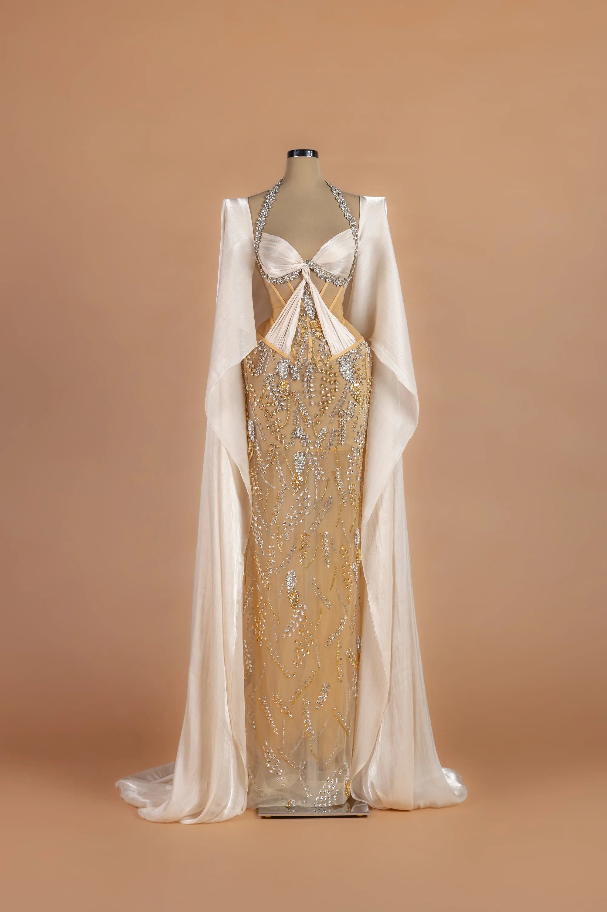 Sihëna Gossamer Moonrise — champagne halter cape-sleeve column gown with a crystal-trimmed corset bodice.