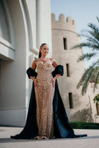 Sihëna Nacre Penumbra — champagne strapless sleeveless column gown with a crystal bodice and a separate black satin cape.