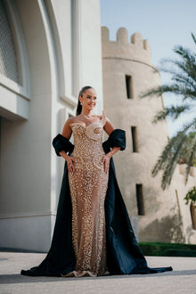 Sihëna Nacre Penumbra — champagne strapless sleeveless column gown with a crystal bodice and a separate black satin cape.