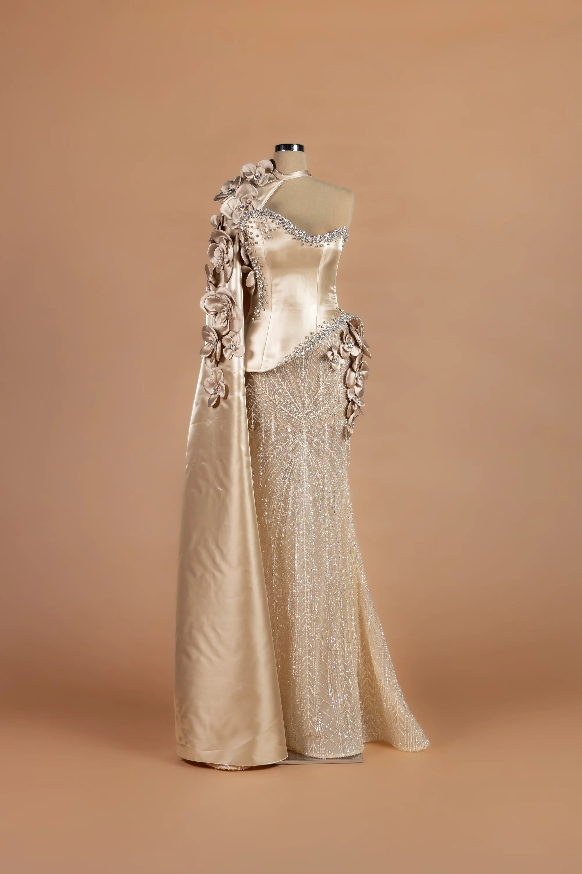 Sihëna Oyster Orchid — champagne asymmetric sleeveless column gown with a satin cape of crystal-studded 3D florals.