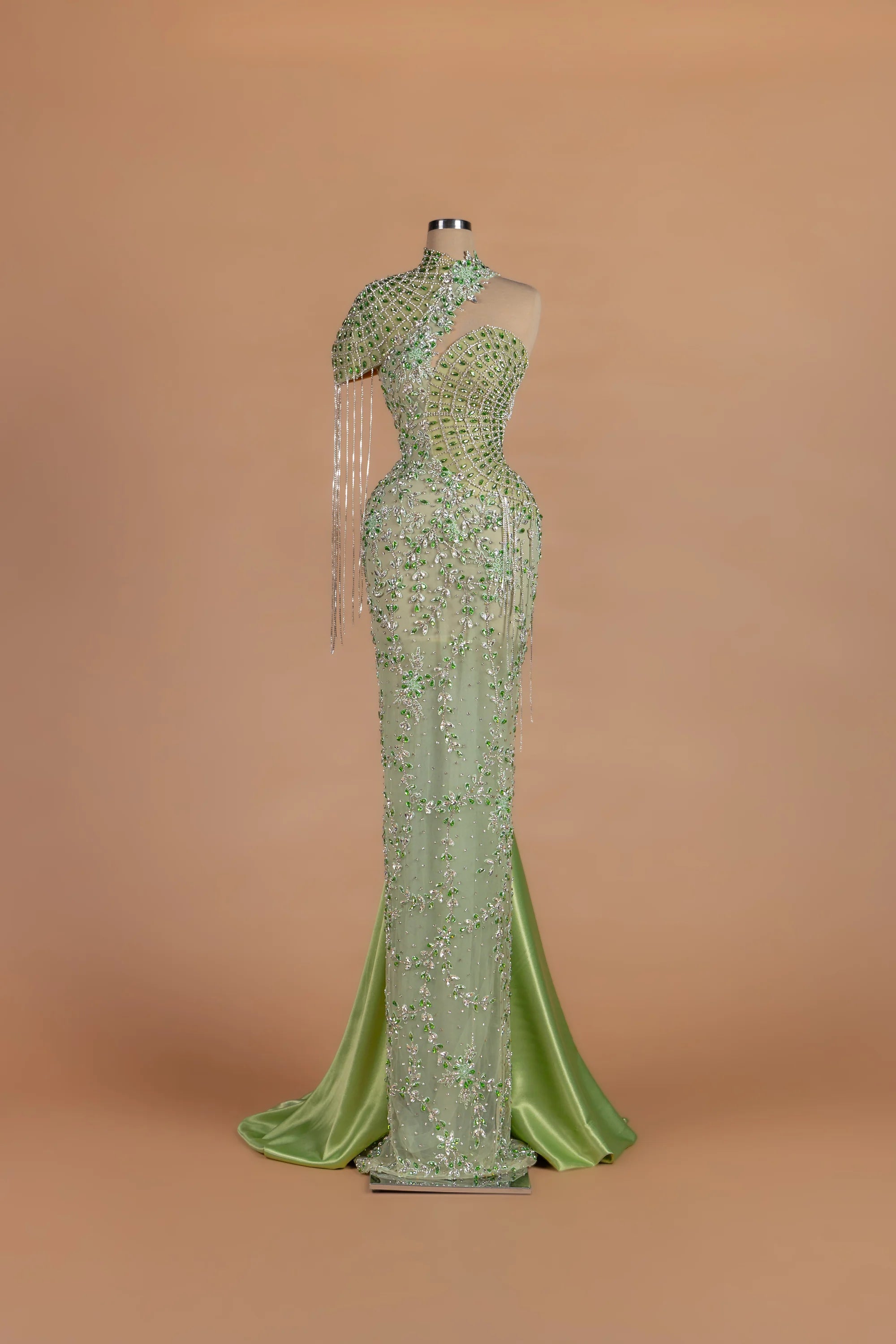 Sihëna Peacock Regalia — sage-green asymmetric sleeveless mermaid gown with crystal beading.