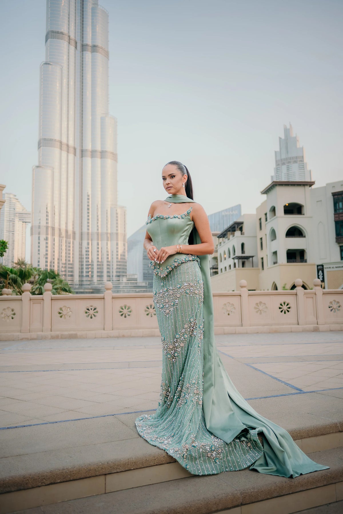 Sihëna Seaglass Idyll — sage-green square-neck spaghetti-strap column gown with pearl floral beading and a satin cape.